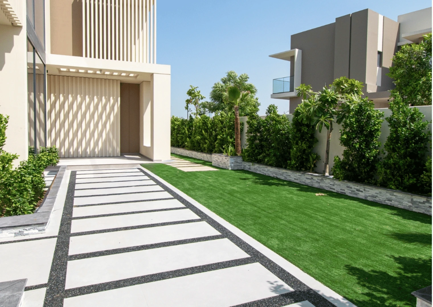 Landscaping in Dubai: villa entrance walkway with artificial grass and hedges