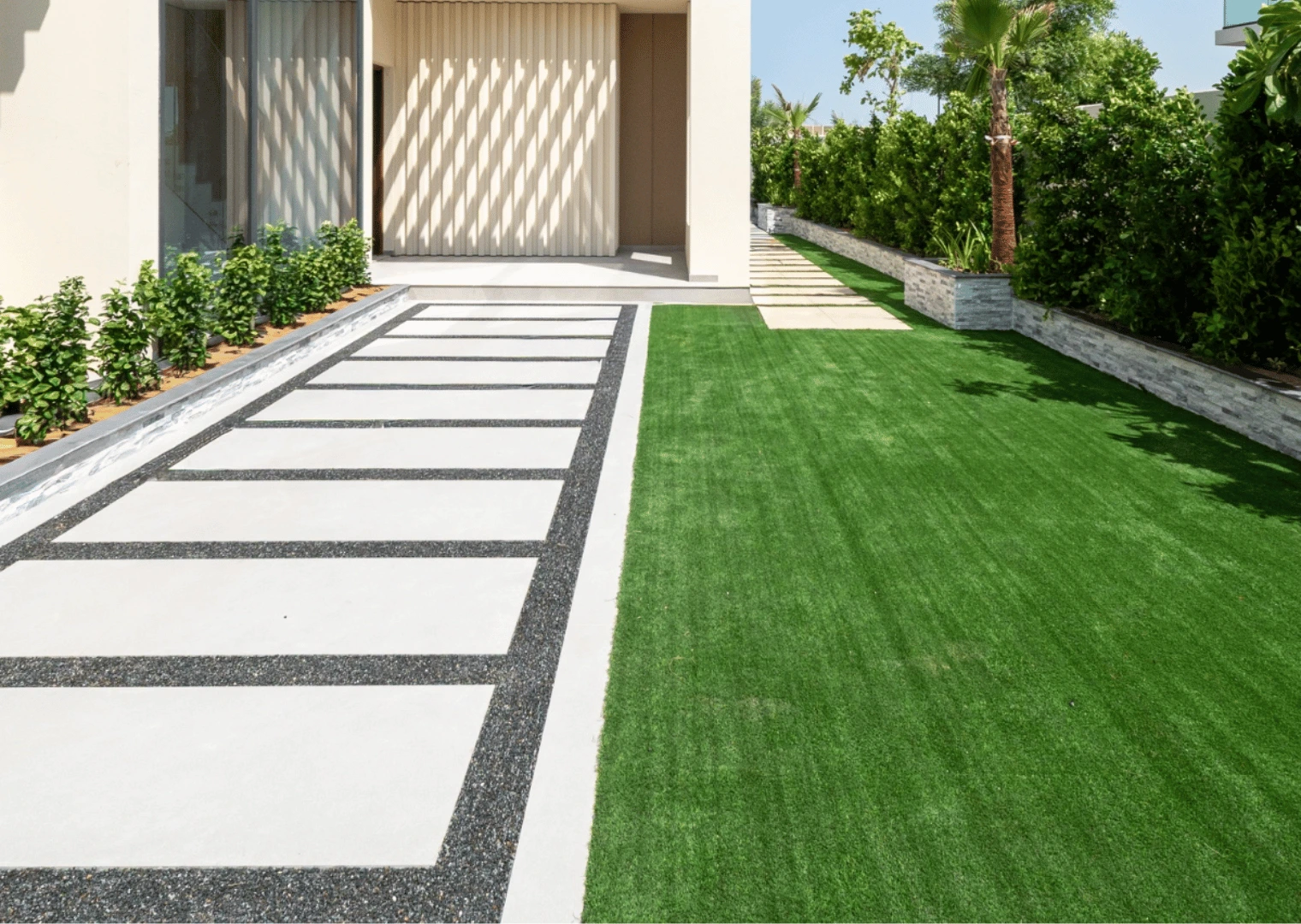 Paved garden path with stone-clad planter and hedge border in Dubai