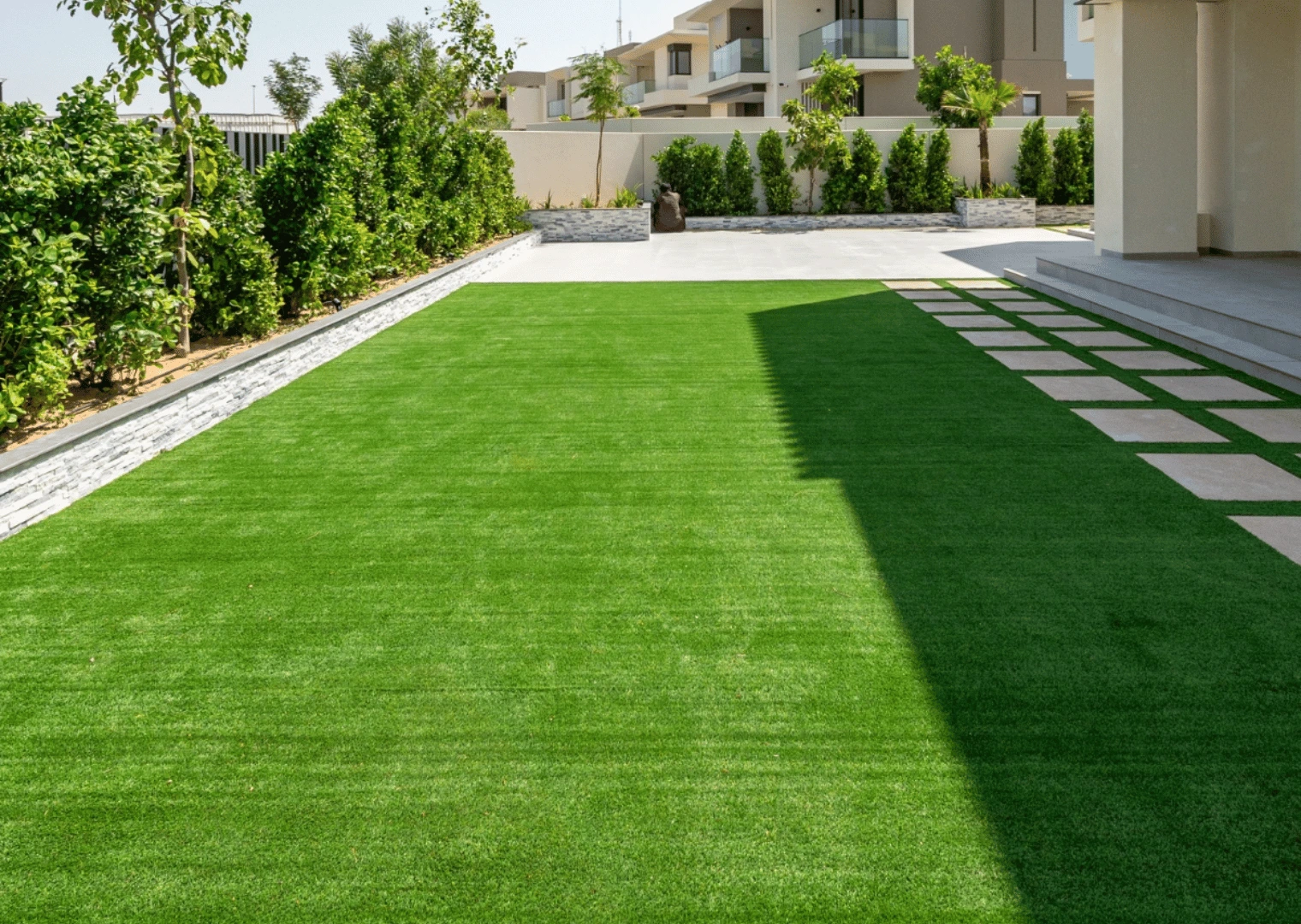 Villa backyard artificial lawn with stepping stones and hedges in Dubai